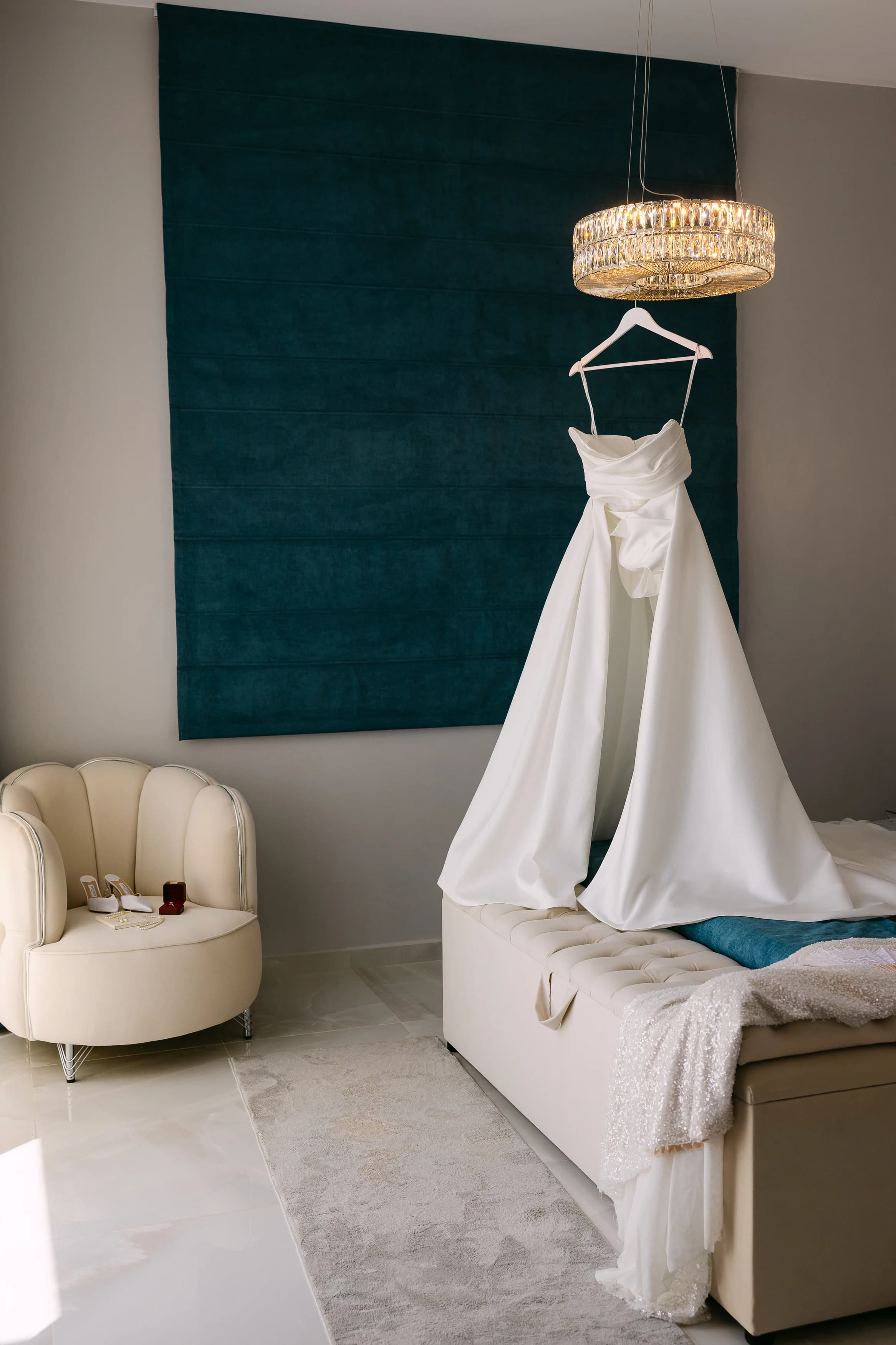 Wedding dress hanging beneath a crystal chandelier in the bridal suite at OZEA.