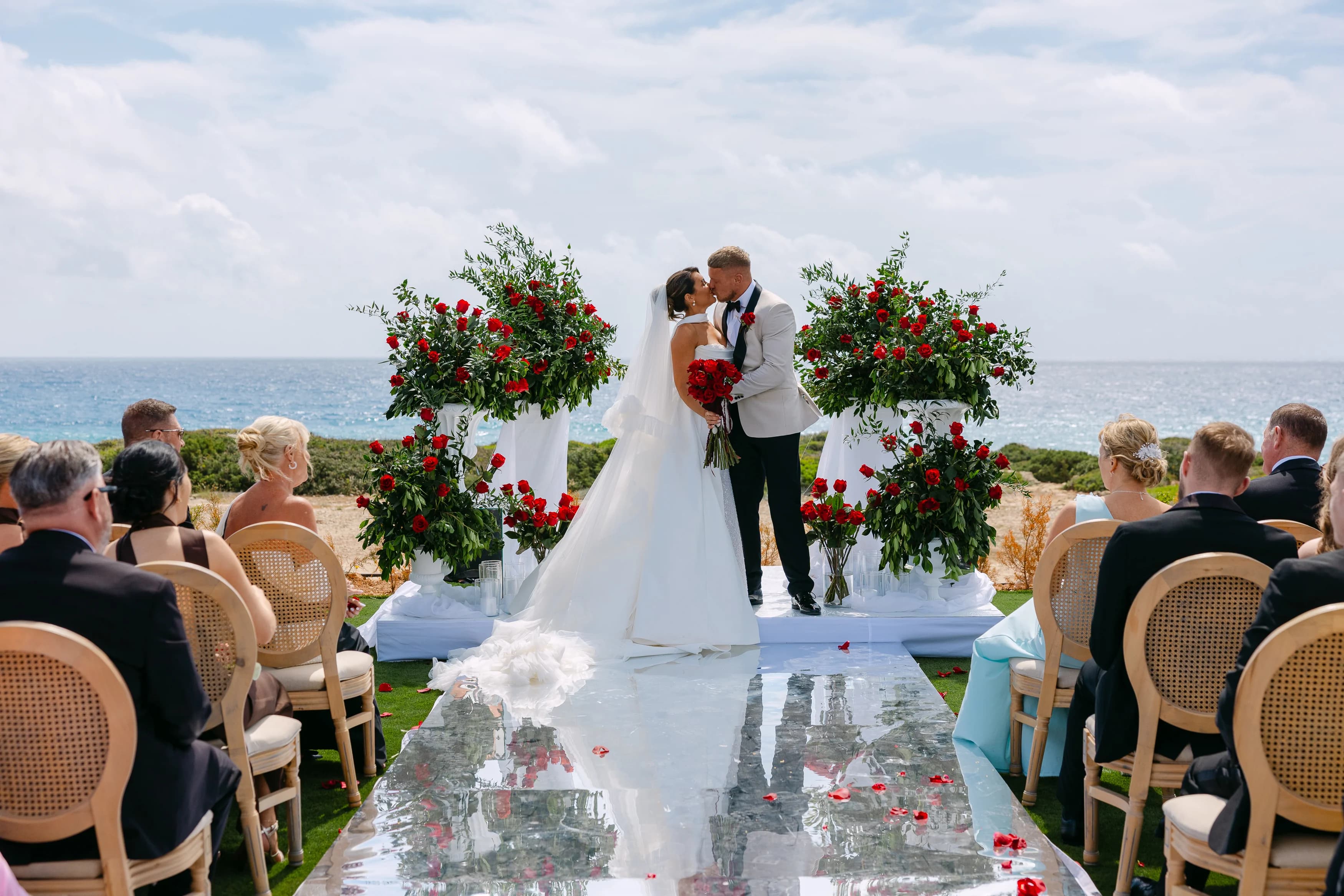 Couple kissing at the floral altar during a sea-view ceremony at OZEA Paphos.