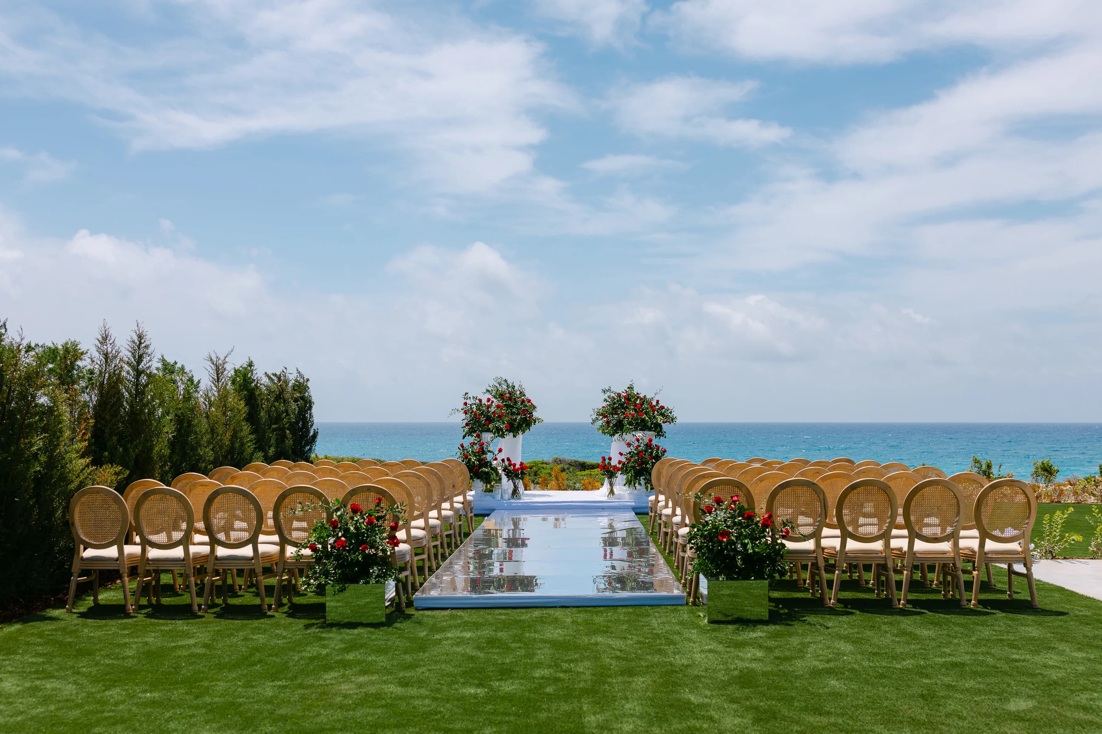 Wide view of the wedding ceremony aisle at OZEA with chairs facing the sea and floral arrangements at the altar.