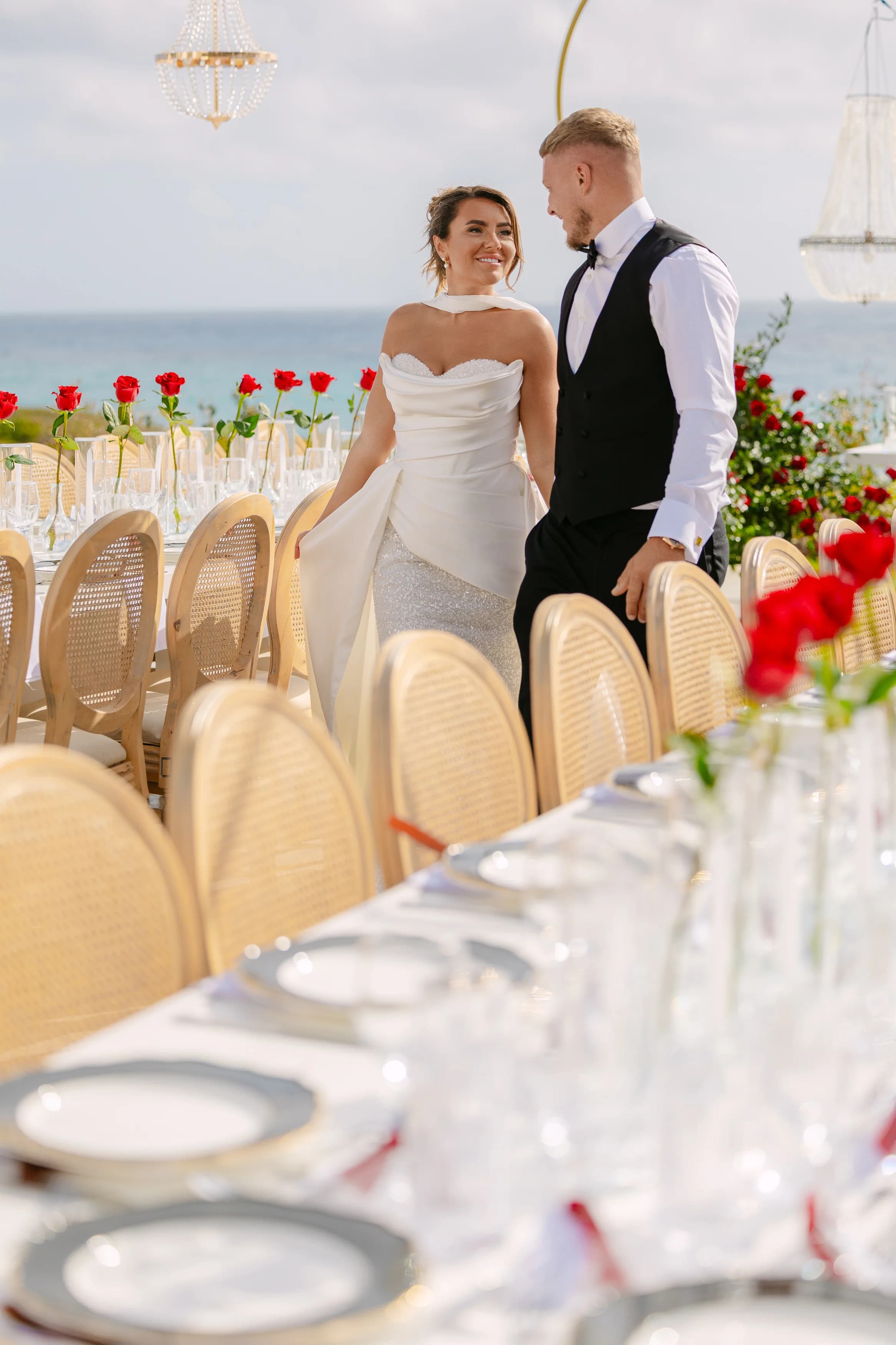 Bride and groom standing close to the banquet table at Ozea with chandelier light overhead.