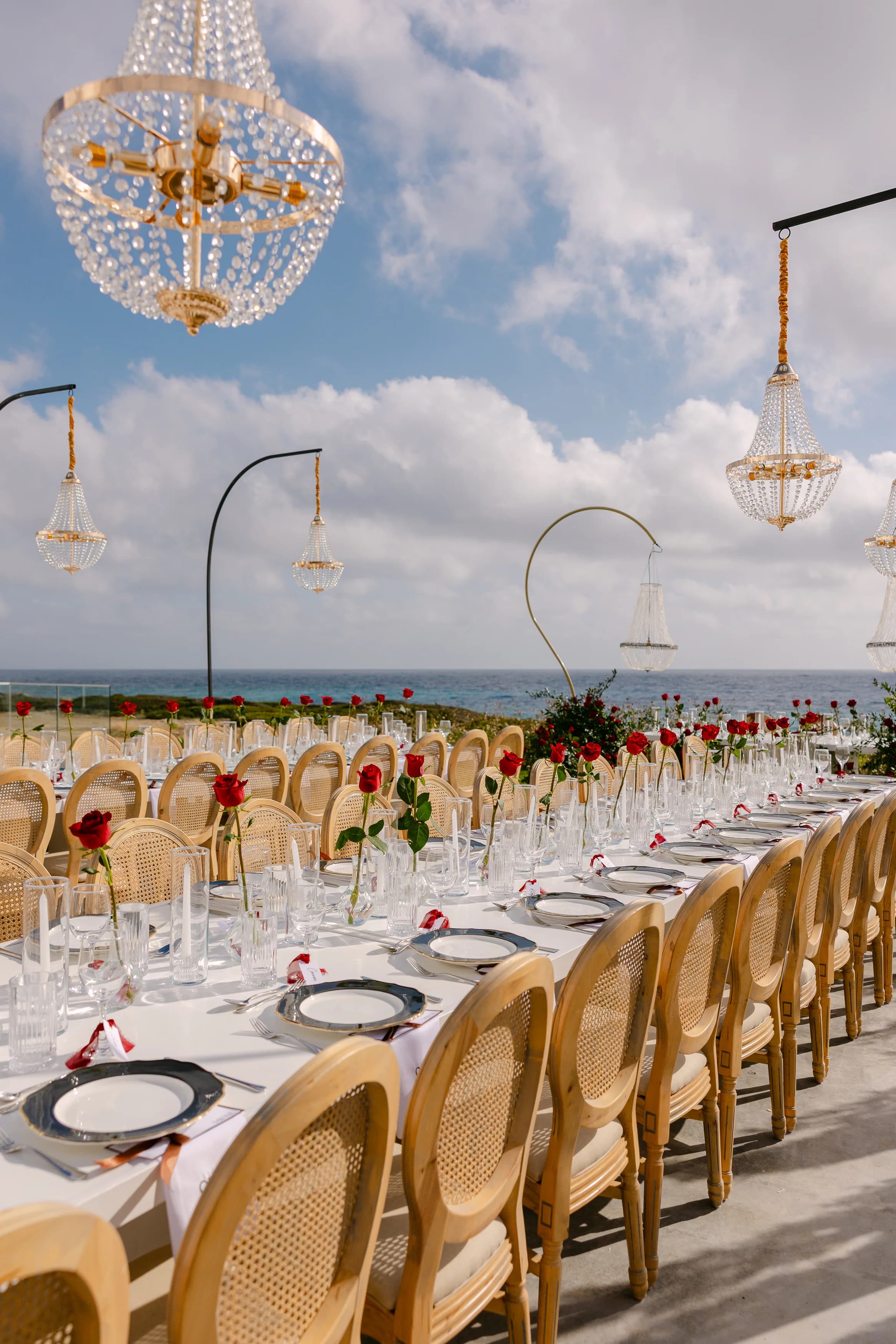 Close view of the crystal chandeliers above the banquet table at OZEA with the sea behind.