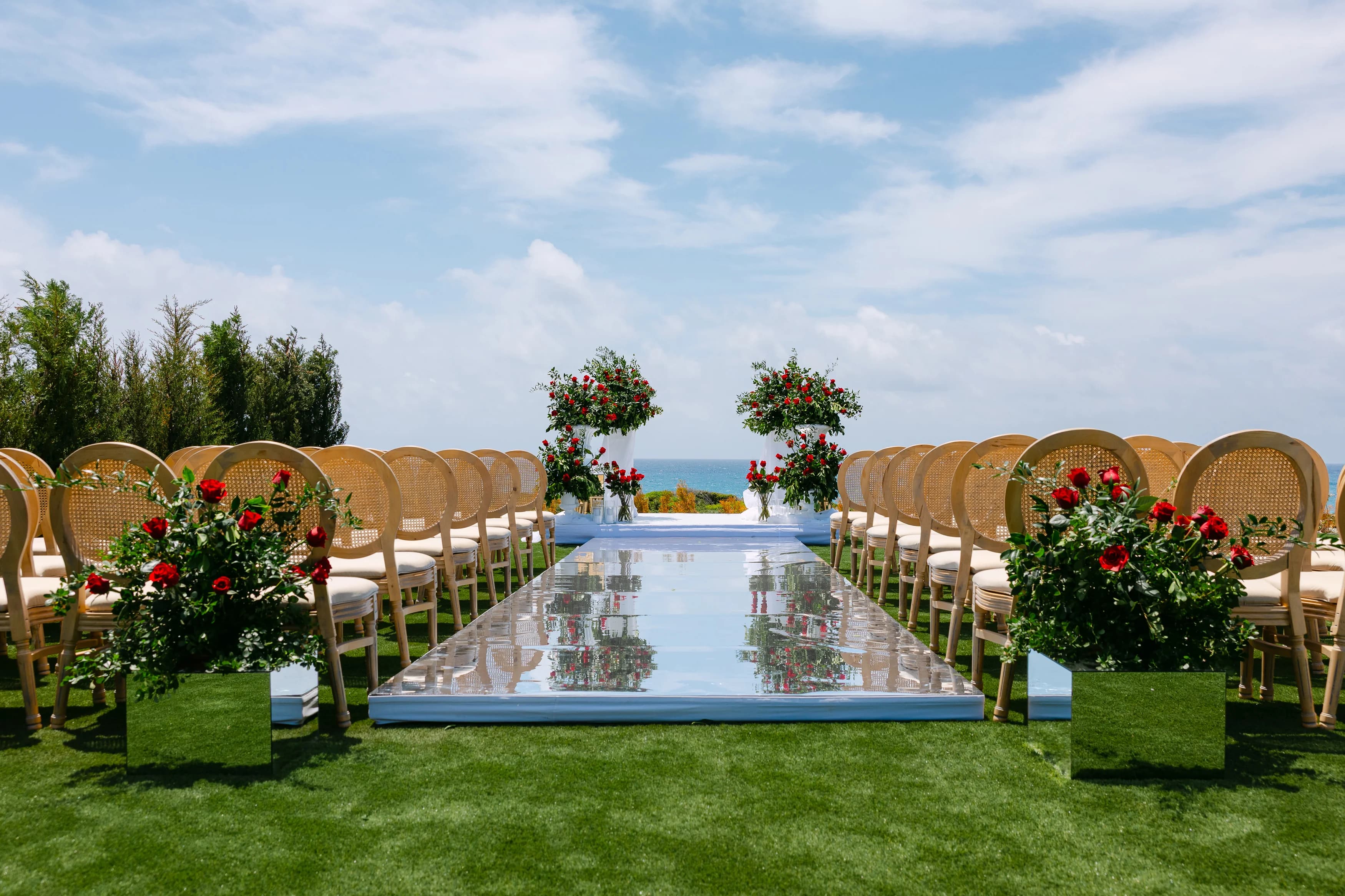 Close perspective of the ceremony aisle at Ozea with floral pedestals and the sea horizon.
